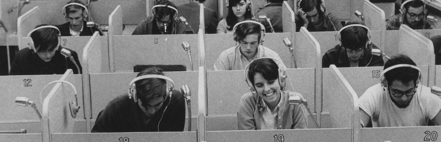 A language lab, with students seated in soundproof partitions, headphones on